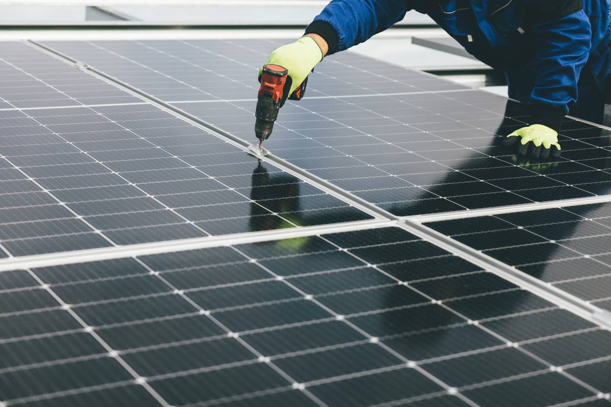 how to start using solar panels: rooftop solar array on suburban home with clear sky background